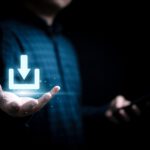 Eine Person hält eine geöffnete Handfläche hoch, über der ein leuchtend blau-weißes Download-Symbol schwebt.
