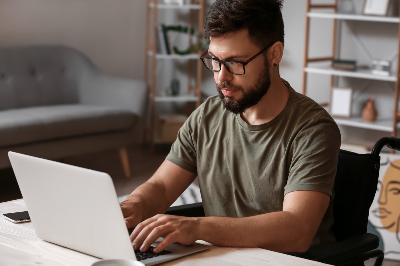 Ein junger Mann mit Brille und Bart arbeitet an einem Laptop.