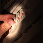 Eine Hand betätigt im Schein einer Taschenlampe einen Kippschalter in einem Sicherungskasten.